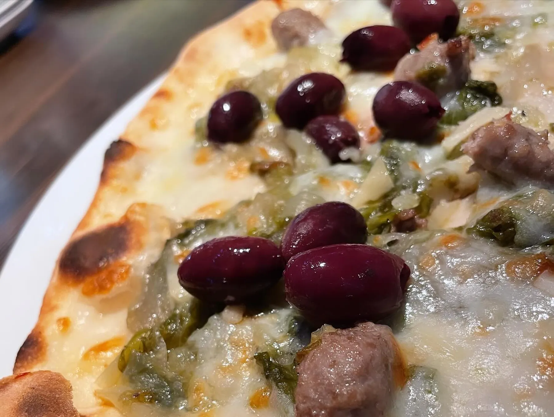 Pizza mit Oliven, Salsiccia und Friarielli, Rand mit Leopardenmuster